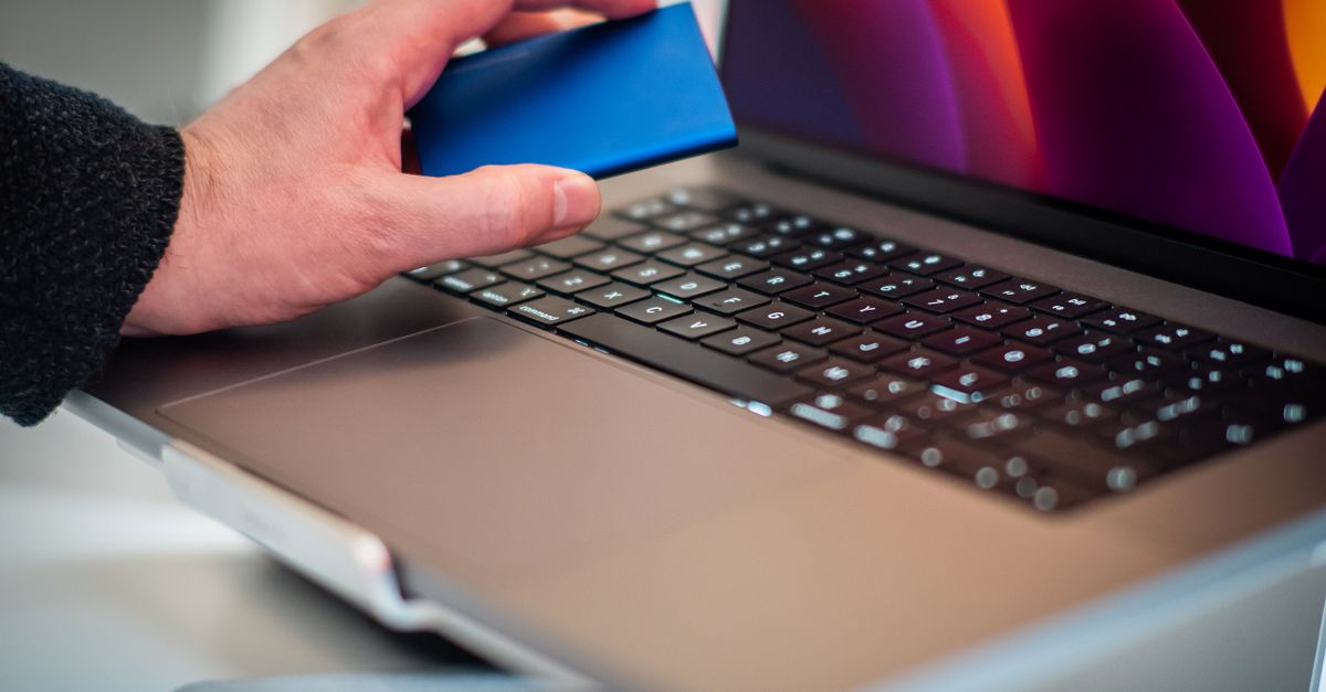 Mano che regge un disco esterno sopra un computer portatile