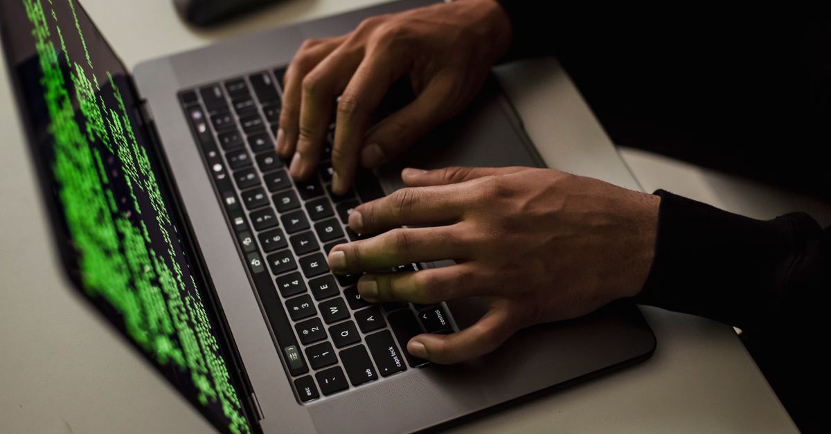 Mani sulla tastiera di un computer con codice sullo schermo